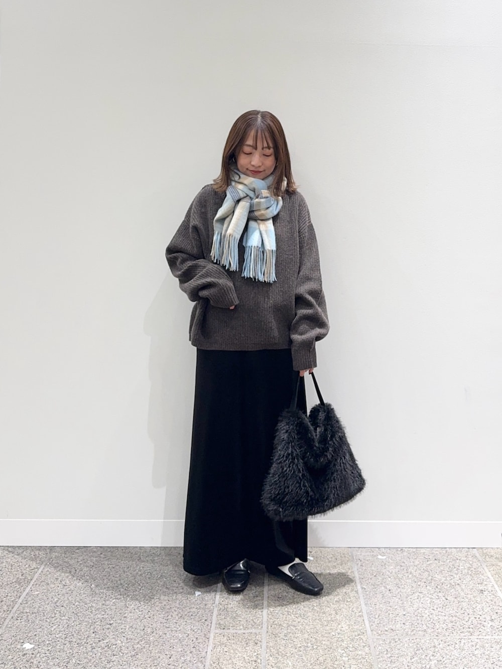 ブラウン系のニット/セーター、ブラック系のスカート、ブラック系のハンドバッグを着用したレディースの秋コーディネートの3枚目の写真