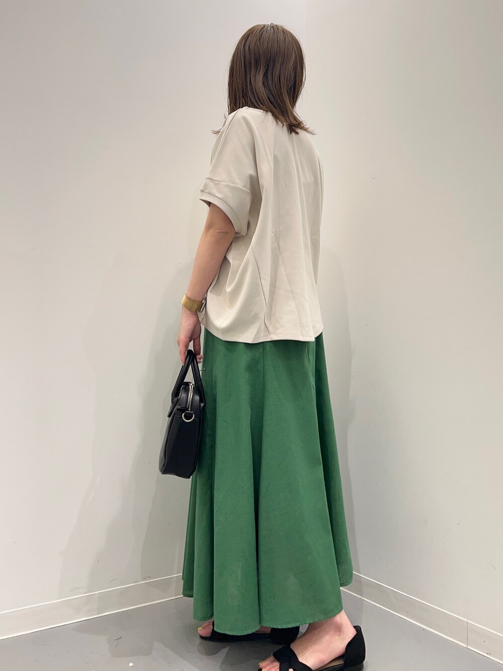 グレー系のTシャツ/カットソー、ブラック系のサンダル、グリーン系のスカートを着用したレディースの春コーディネートの3枚目の写真