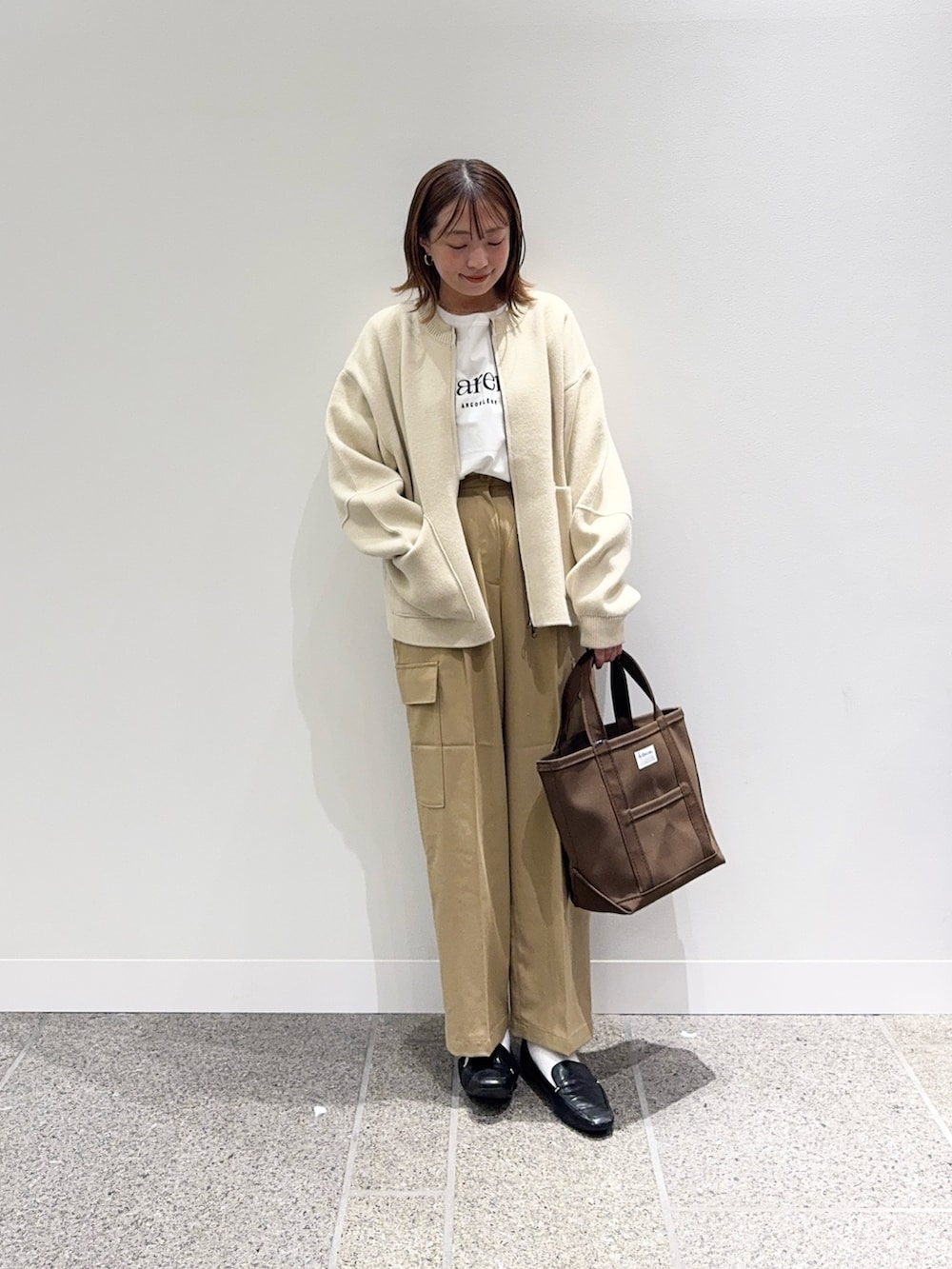 ベージュ系のニット/セーター、ホワイト系のTシャツ/カットソー、ブラウン系のトートバッグを着用したレディースの秋コーディネートの5枚目の写真