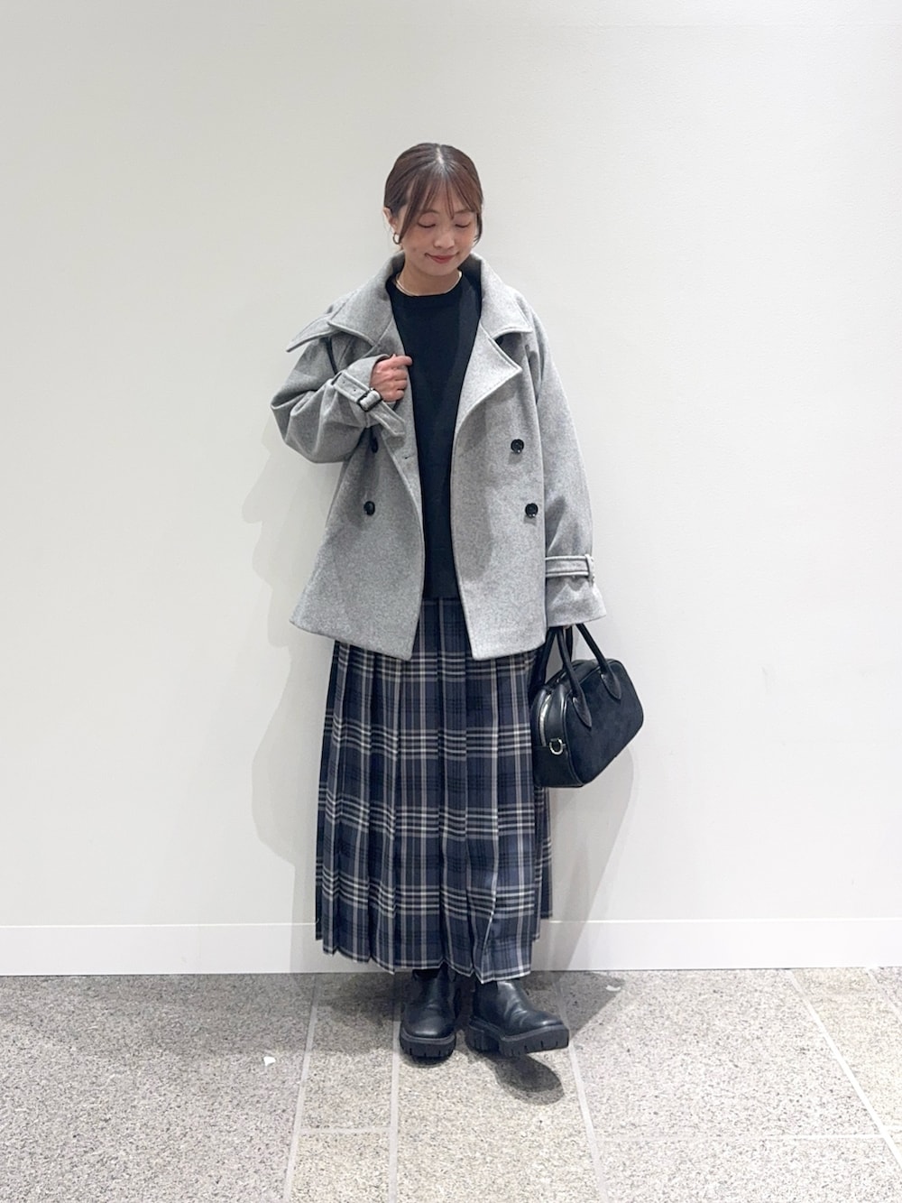 グレー系のその他アウター、ブラック系のニット/セーター、グレー系のスカートを着用したレディースの秋コーディネートの2枚目の写真