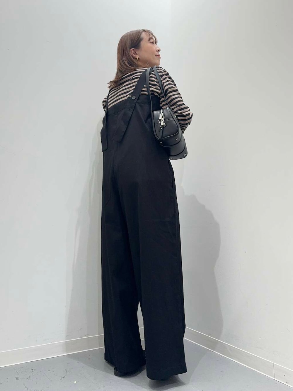 ブラック系のその他シューズ、ブラック系のボストンバッグ、オレンジ系のTシャツ/カットソーを着用したレディースの秋コーディネートの4枚目の写真