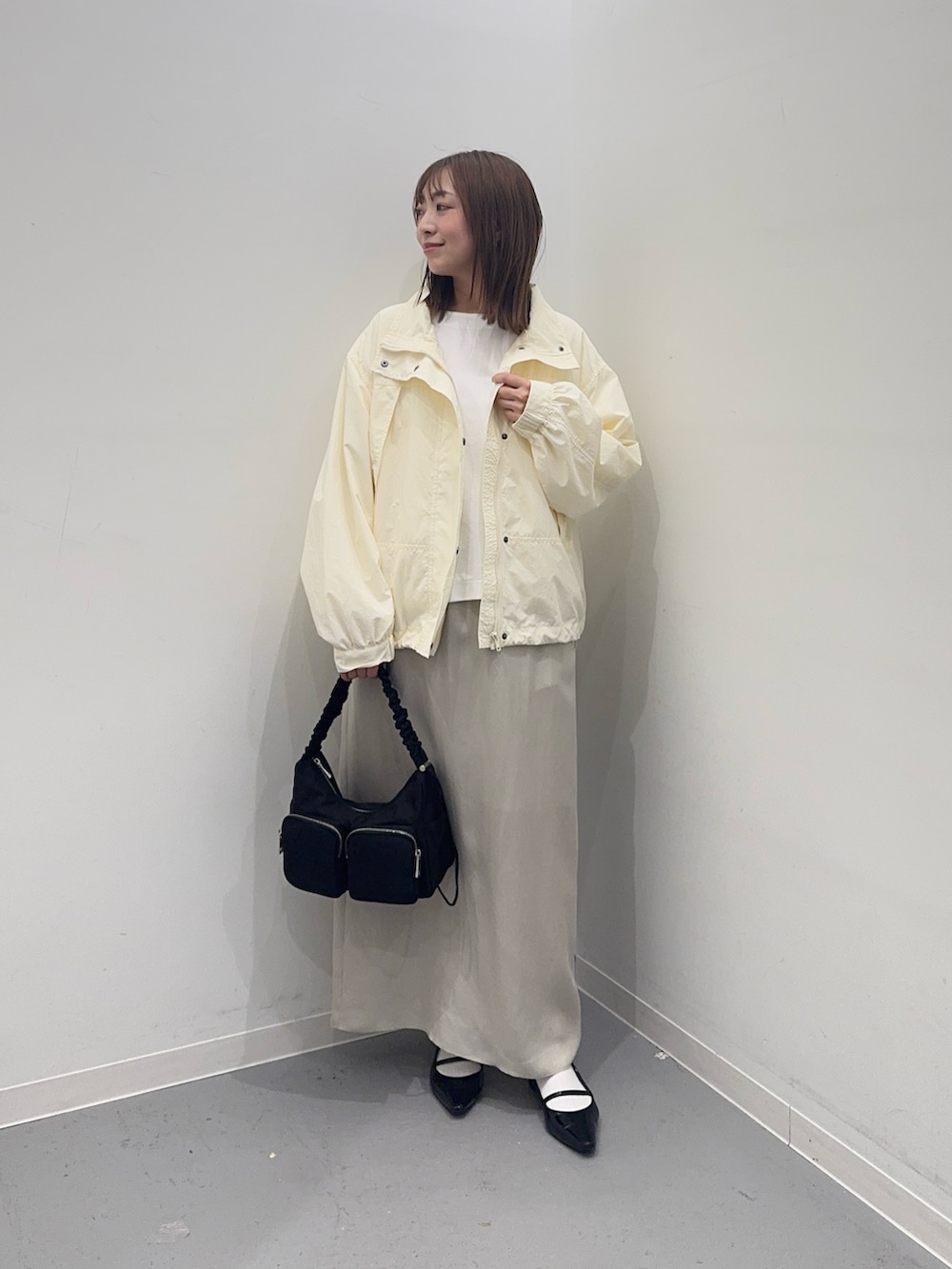 ホワイト系のナイロンジャケット、ベージュ系のスカート、ホワイト系のTシャツ/カットソーを着用したレディースの春コーディネートの3枚目の写真
