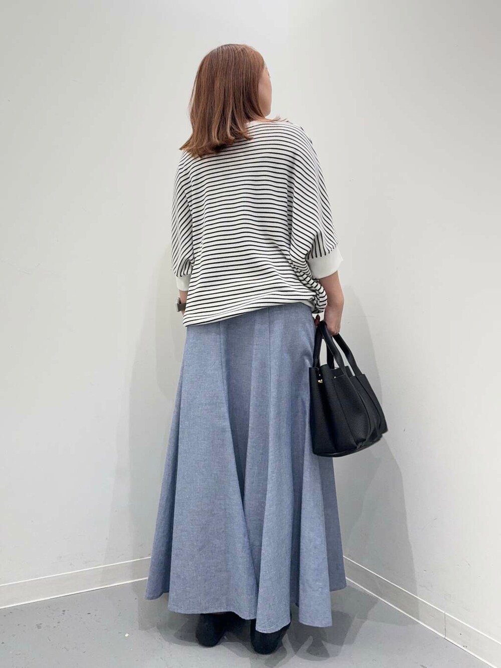 ブラック系のローファー、ブラック系のトートバッグ、ホワイト系のTシャツ/カットソーを着用したレディースの夏コーディネートの3枚目の写真