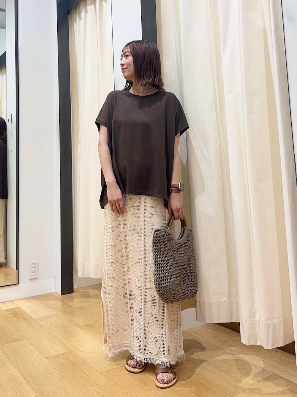 ブラウン系のサンダル、グレー系のトートバッグ、ホワイト系のスカートを着用したレディースの夏コーディネートの2枚目の写真