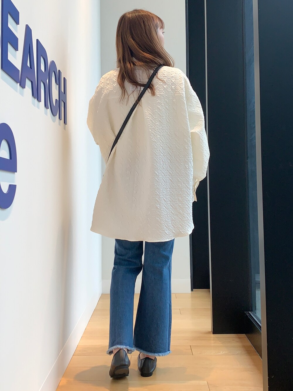 ホワイト系のシャツ/ブラウス、ブルー系のデニムパンツ、ブラック系のバレエシューズを着用したレディースの冬コーディネートの4枚目の写真