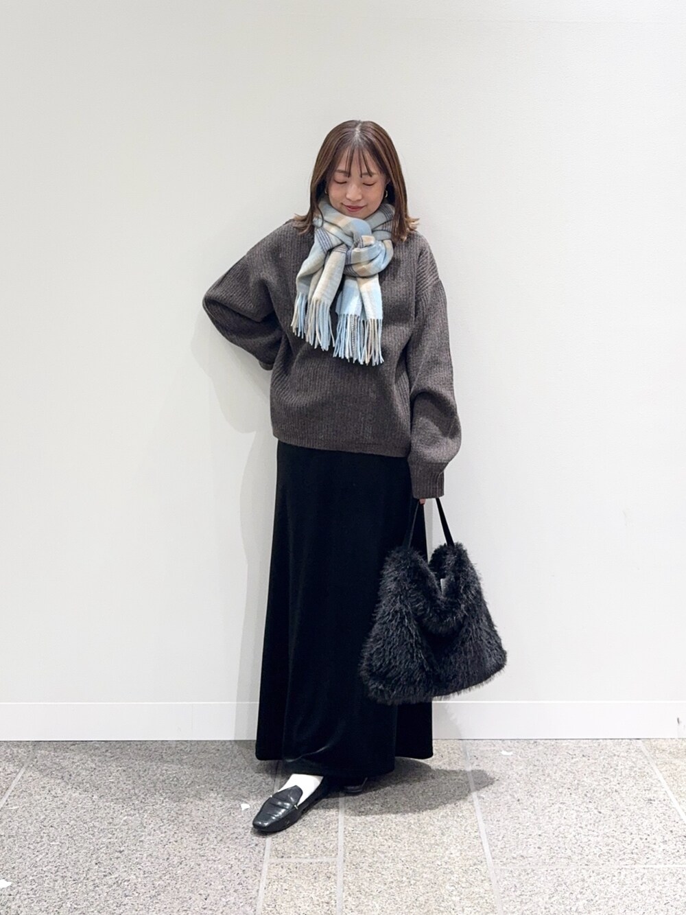 ブラウン系のニット/セーター、ブラック系のスカート、ブラック系のハンドバッグを着用したレディースの秋コーディネートの6枚目の写真