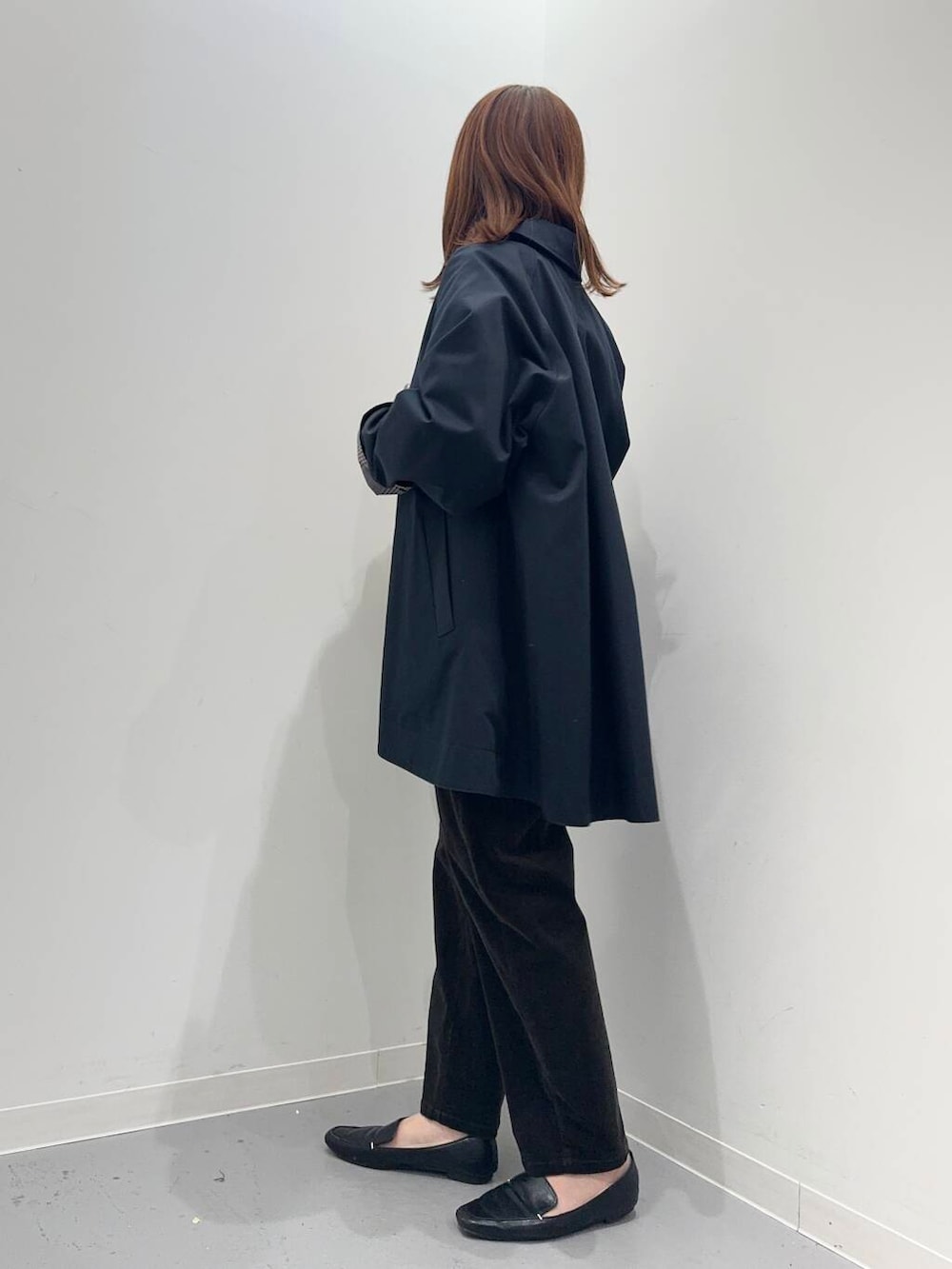 ブラック系のローファー、ブラック系のトートバッグ、ブルー系のステンカラーコートを着用したレディースの秋コーディネートの2枚目の写真