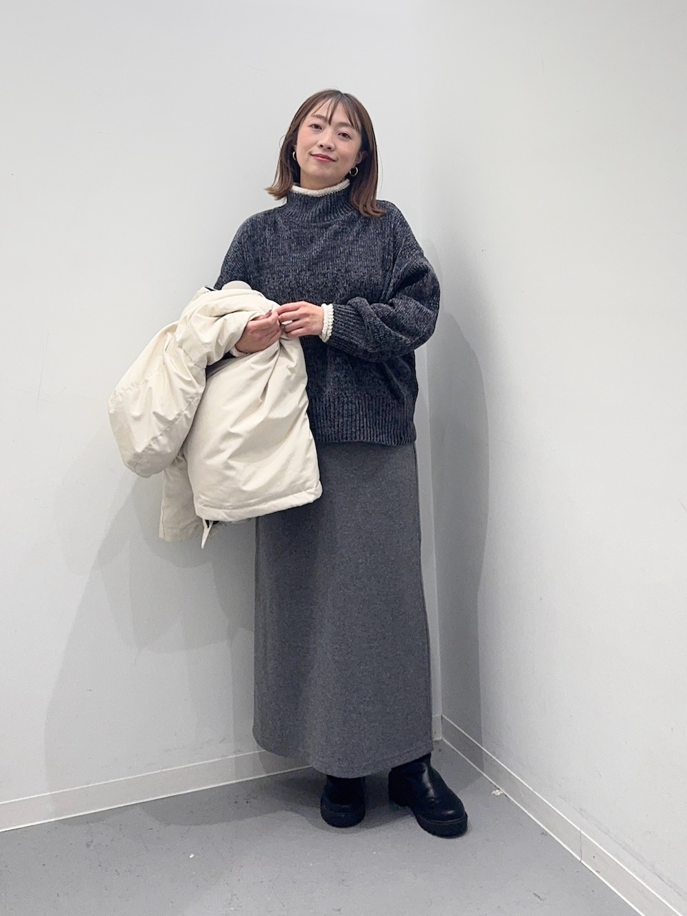 ホワイト系のダウンジャケット/コート、グレー系のニット/セーター、グレー系のスカートを着用したレディースの冬コーディネートの6枚目の写真