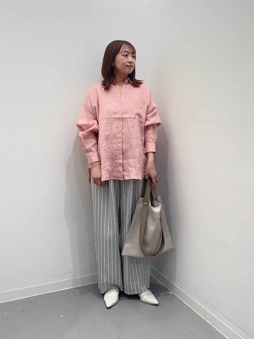 ピンク系のシャツ/ブラウス、グレー系のその他パンツ、ホワイト系のトートバッグを着用したレディースの春コーディネートの2枚目の写真