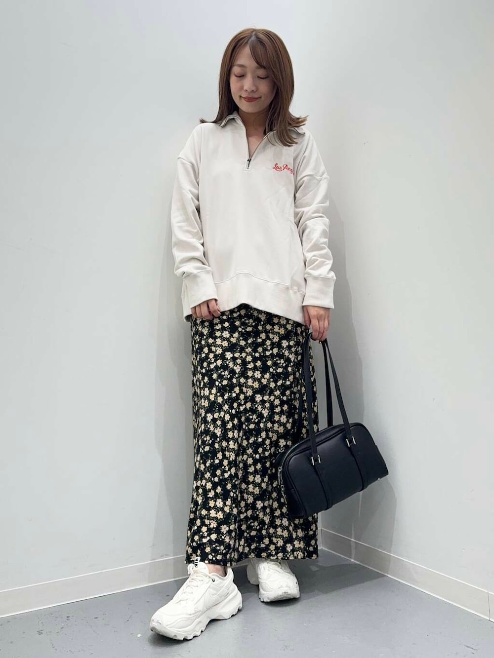ホワイト系のスニーカー、ブラック系のボストンバッグ、ブラック系のスカートを着用したレディースの秋コーディネートの4枚目の写真