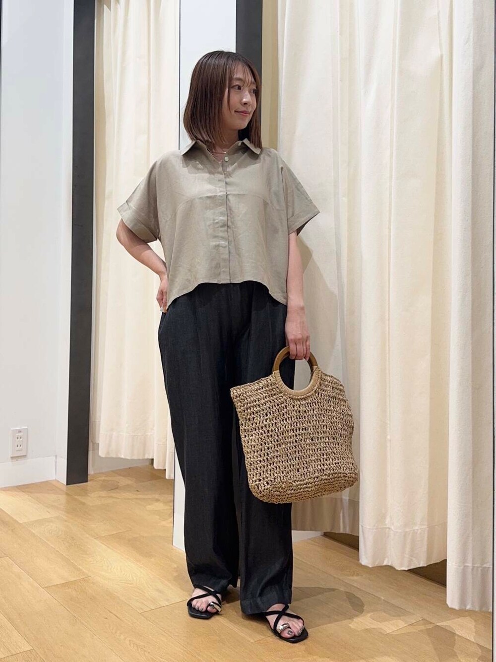 ベージュ系のトートバッグ、ブラック系のデニムパンツ、ブラック系のサンダルを着用したレディースの夏コーディネートの2枚目の写真