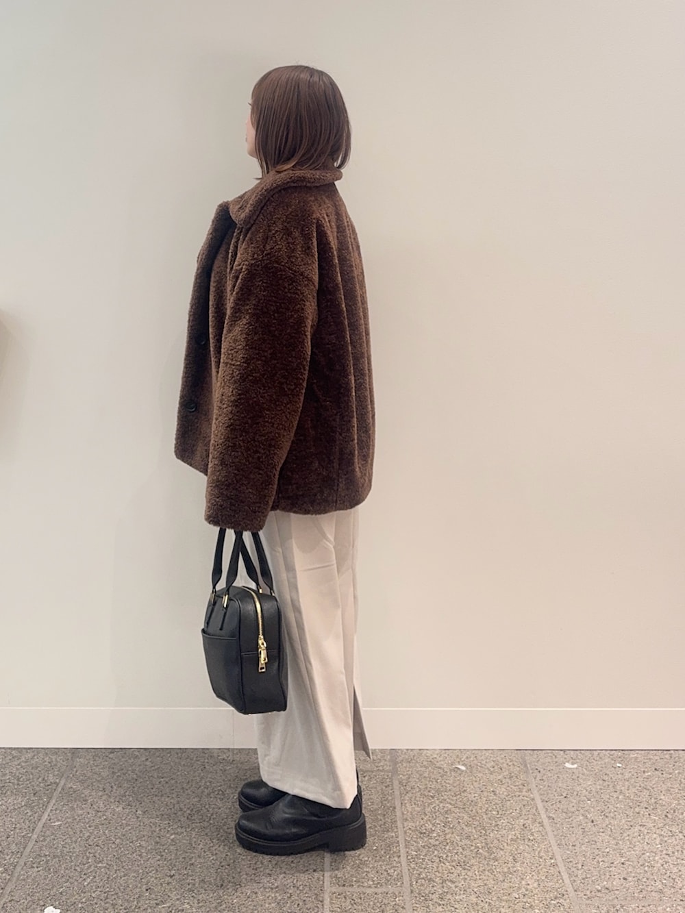 ブラウン系のその他アウター、ホワイト系のニット/セーター、ブラック系のボストンバッグを着用したレディースの冬コーディネートの2枚目の写真