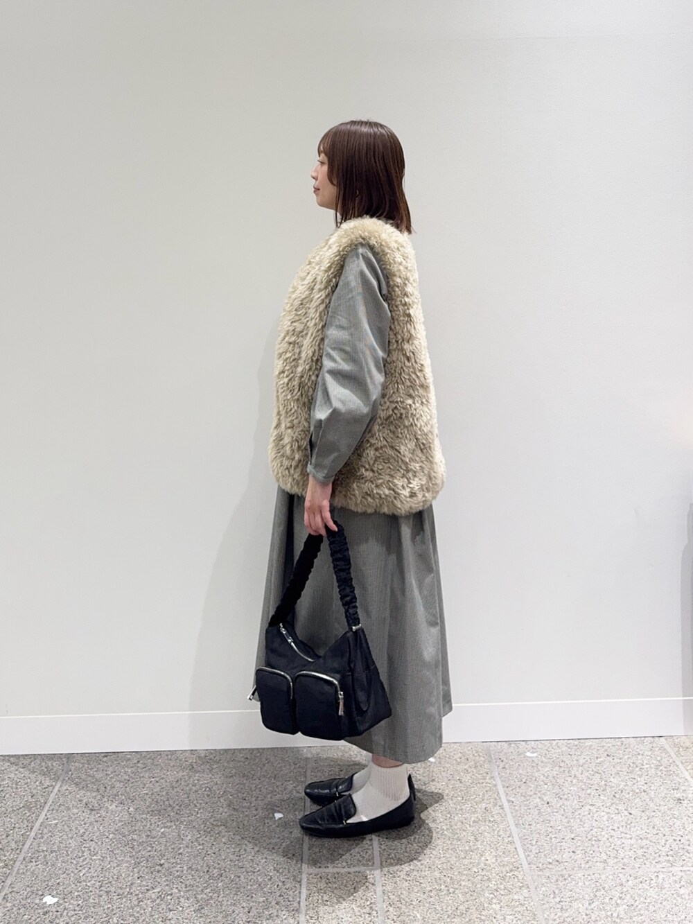 グレー系のワンピース、ベージュ系のその他アウター、ブラック系のショルダーバッグを着用したレディースの秋コーディネートの6枚目の写真