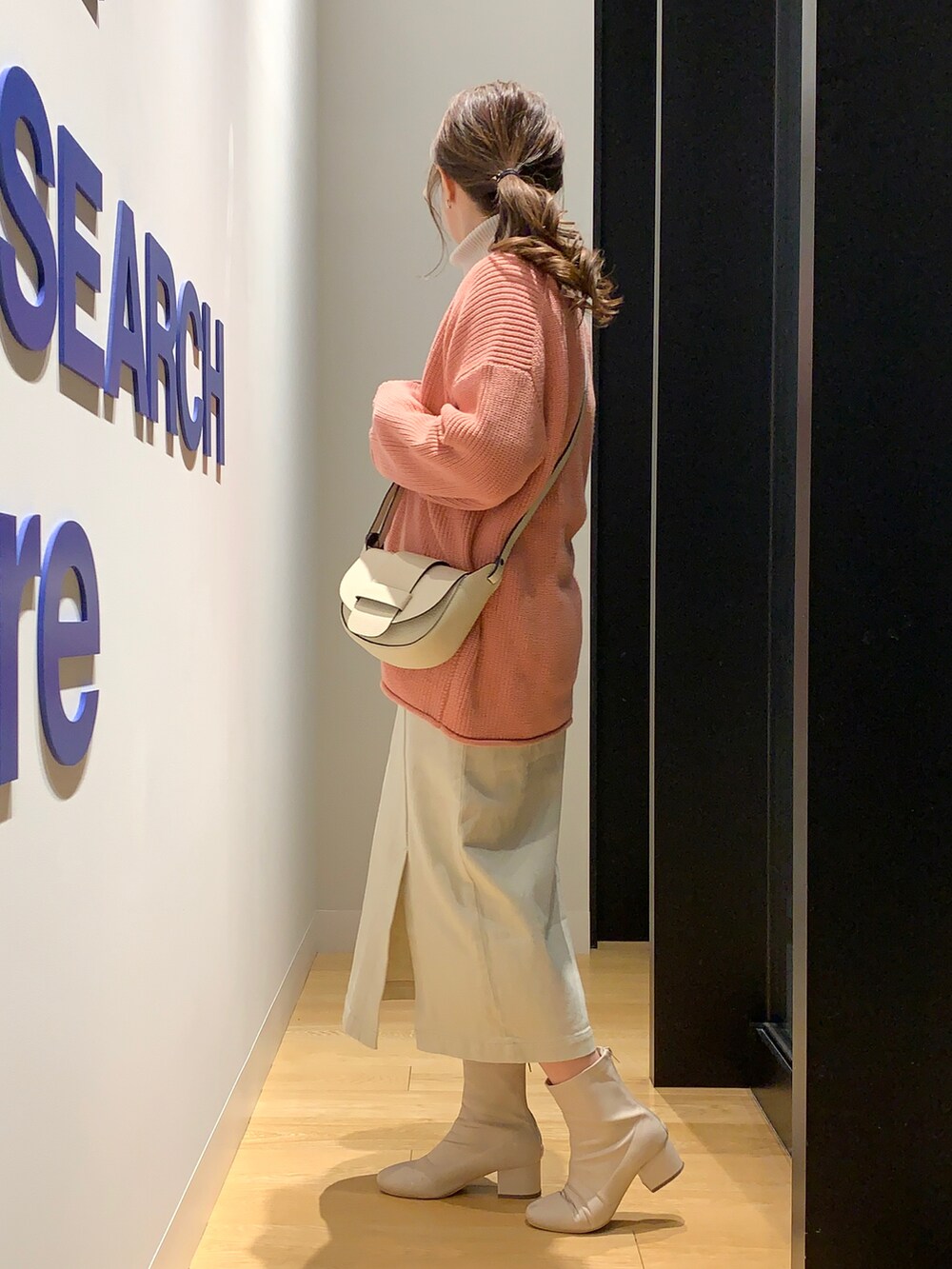 ピンク系のカーディガン/ボレロ、グレー系のニット/セーター、ベージュ系のスカートを着用したレディースの冬コーディネートの2枚目の写真