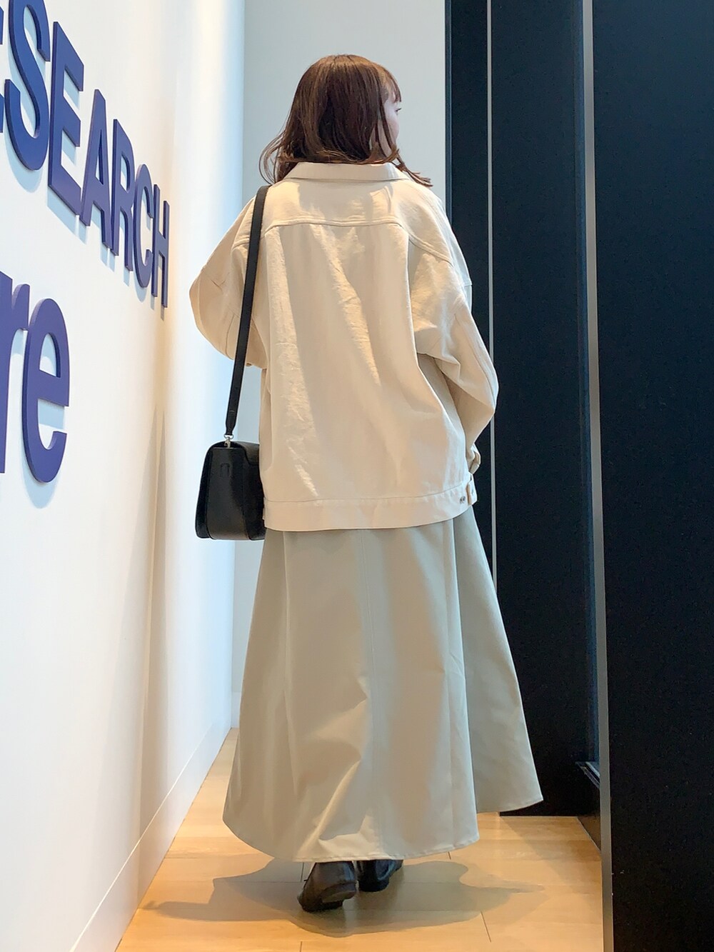 ベージュ系のカバーオール、ブルー系のニット/セーター、グリーン系のスカートを着用したレディースの春コーディネートの3枚目の写真