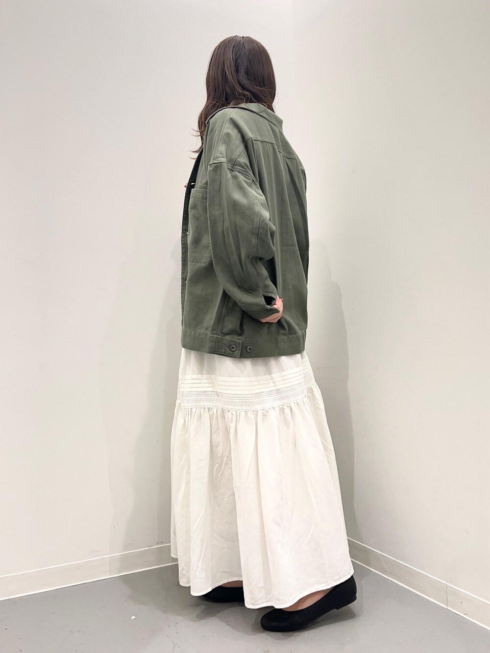 グリーン系のジャケット/アウター、ブラック系のニット/セーター、ホワイト系のスカートを着用したレディースの夏コーディネートの3枚目の写真