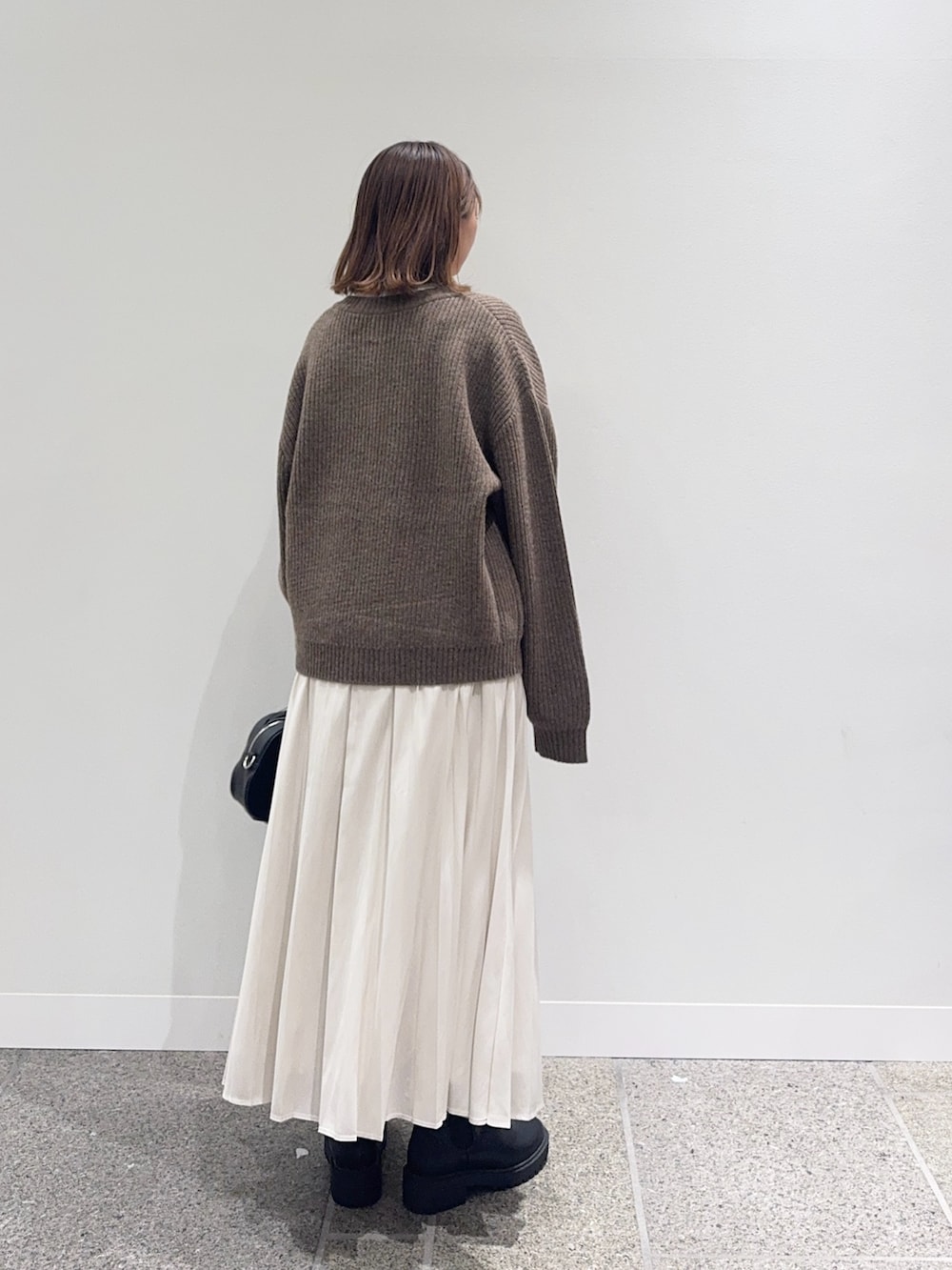 ブラウン系のカーディガン/ボレロ、ホワイト系のスカート、ブラック系のショルダーバッグを着用したレディースの秋コーディネートの3枚目の写真