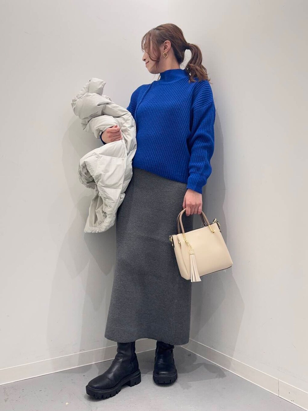 ホワイト系のトートバッグ、ブラック系のブーツ、グレー系のダウンジャケット/コートを着用したレディースの冬コーディネートの8枚目の写真