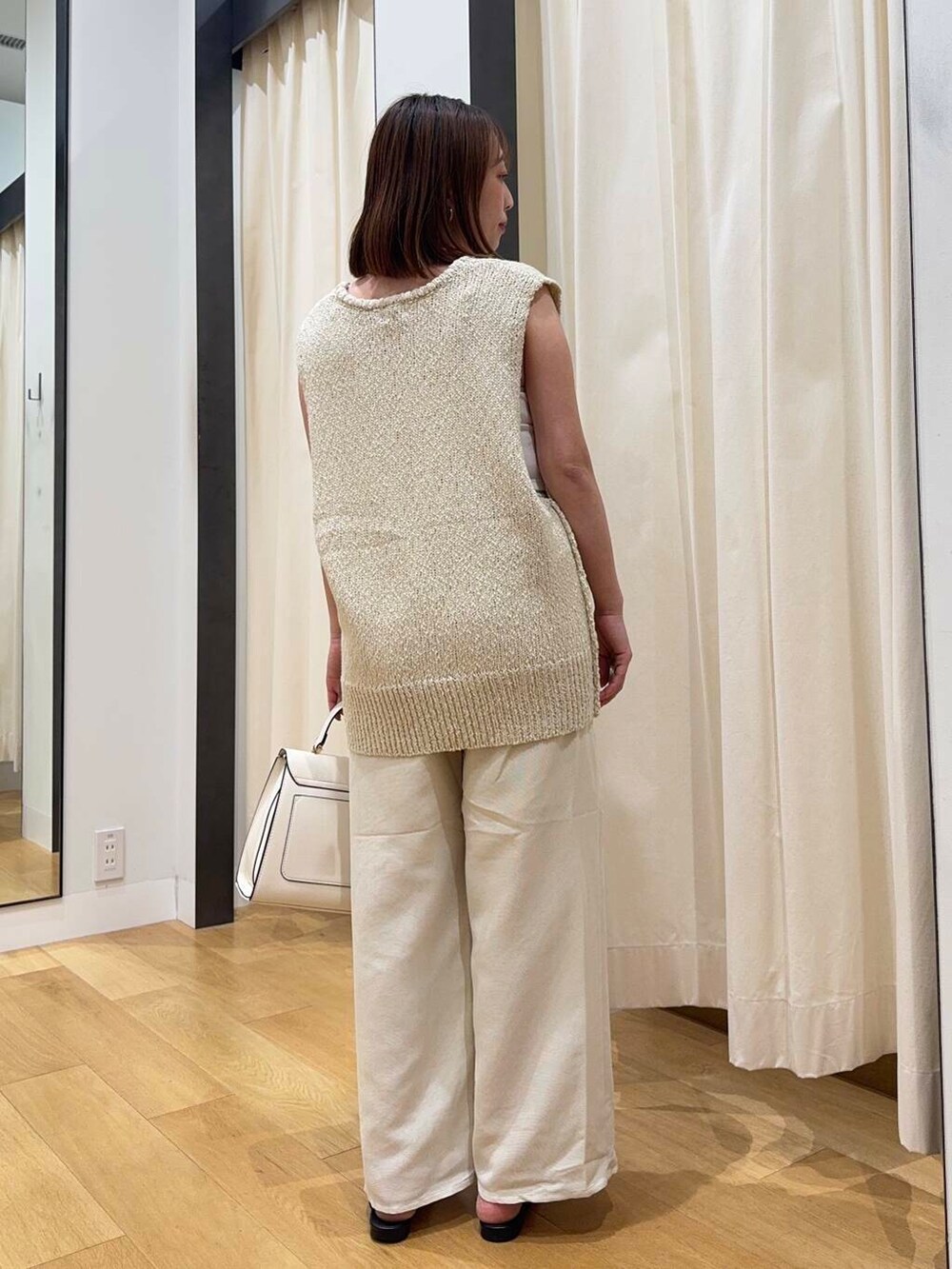 ホワイト系のハンドバッグ、ホワイト系のその他パンツ、ブラック系のローファーを着用したレディースの夏コーディネートの4枚目の写真