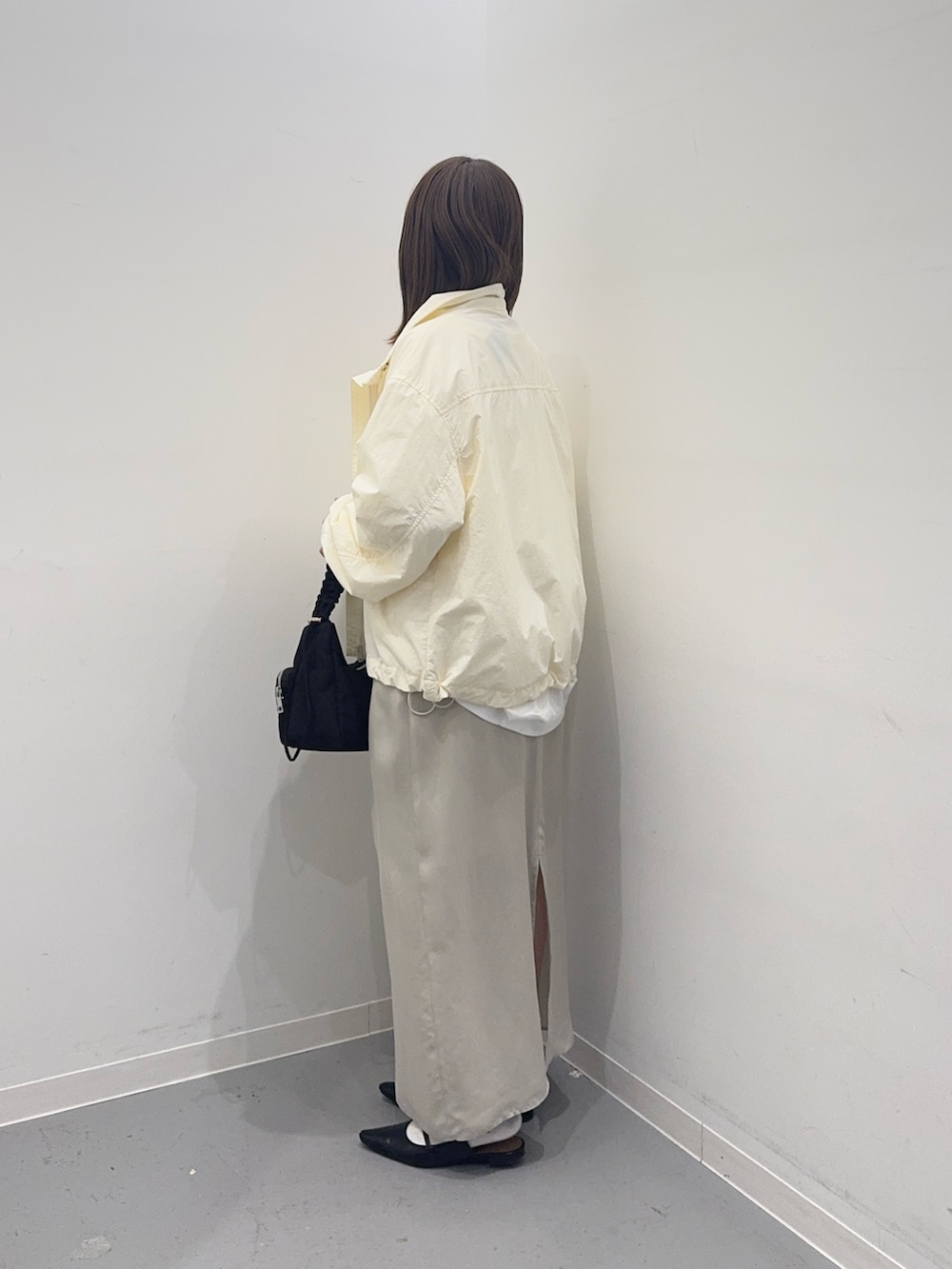 ホワイト系のナイロンジャケット、ベージュ系のスカート、ホワイト系のTシャツ/カットソーを着用したレディースの春コーディネートの2枚目の写真
