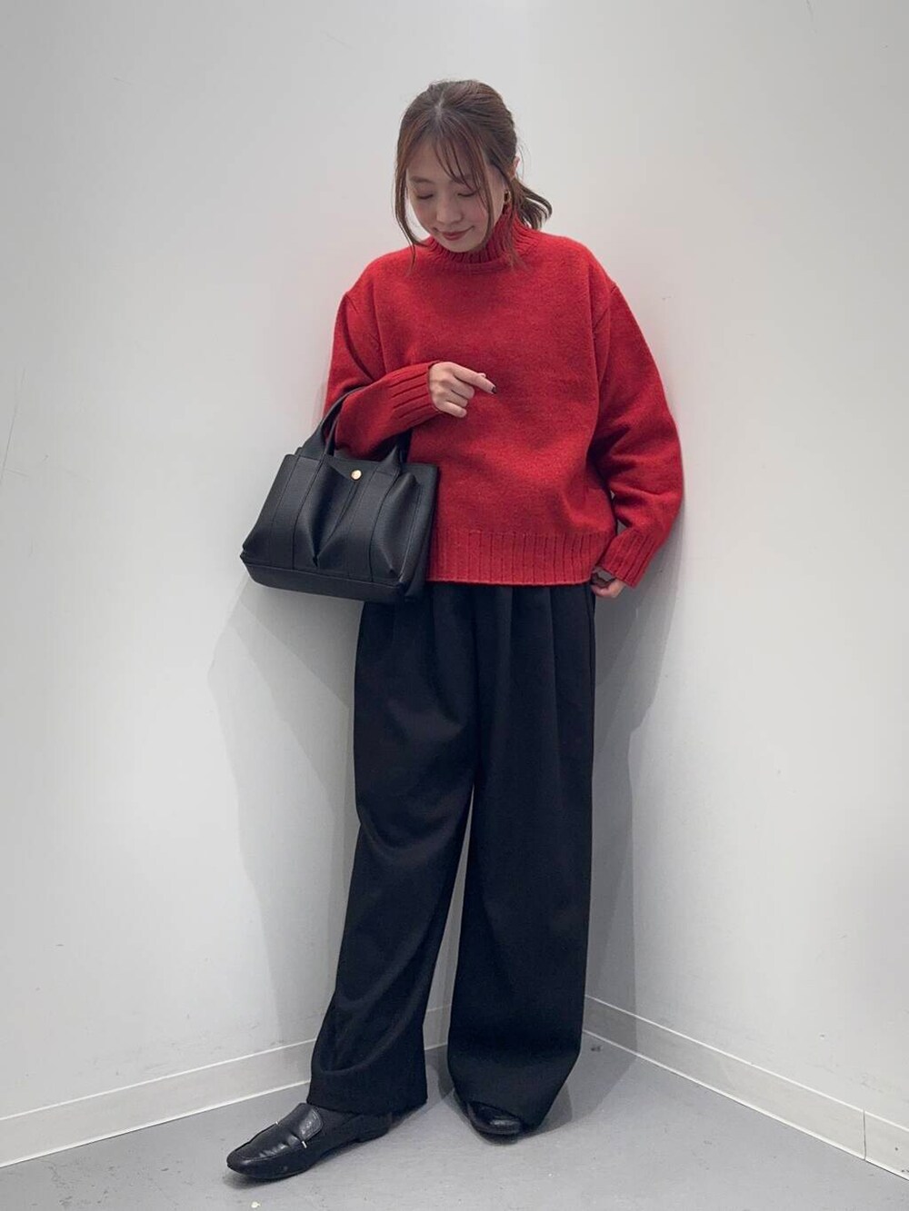 ブラック系のローファー、ブラック系のトートバッグ、レッド系のニット/セーターを着用したレディースの冬コーディネートの2枚目の写真