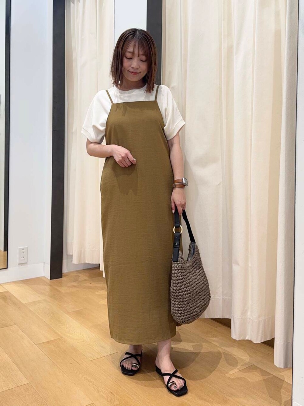 グレー系のトートバッグ、ベージュ系のTシャツ/カットソー、ブラック系のサンダルを着用したレディースの夏コーディネートの2枚目の写真