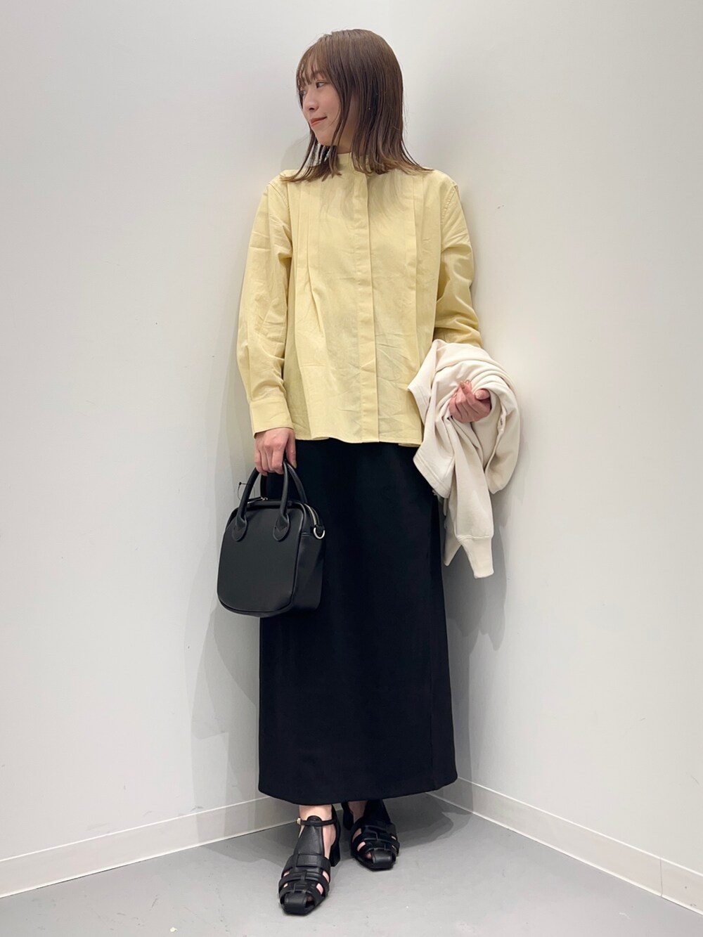 イエロー系のシャツ/ブラウス、ブラック系のスカート、ホワイト系のカーディガン/ボレロを着用したレディースの春コーディネートの7枚目の写真