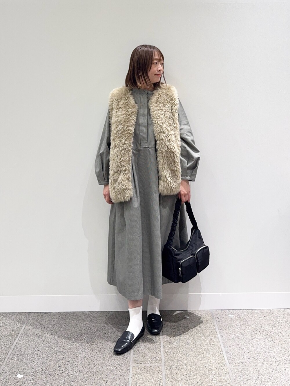 グレー系のワンピース、ベージュ系のその他アウター、ブラック系のショルダーバッグを着用したレディースの秋コーディネートの5枚目の写真