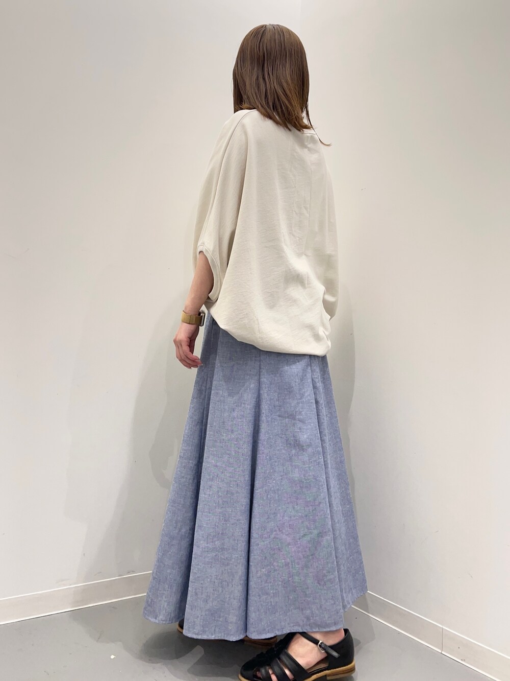 ベージュ系のTシャツ/カットソー、ブルー系のスカート、ブラック系のサンダルを着用したレディースの春コーディネートの5枚目の写真