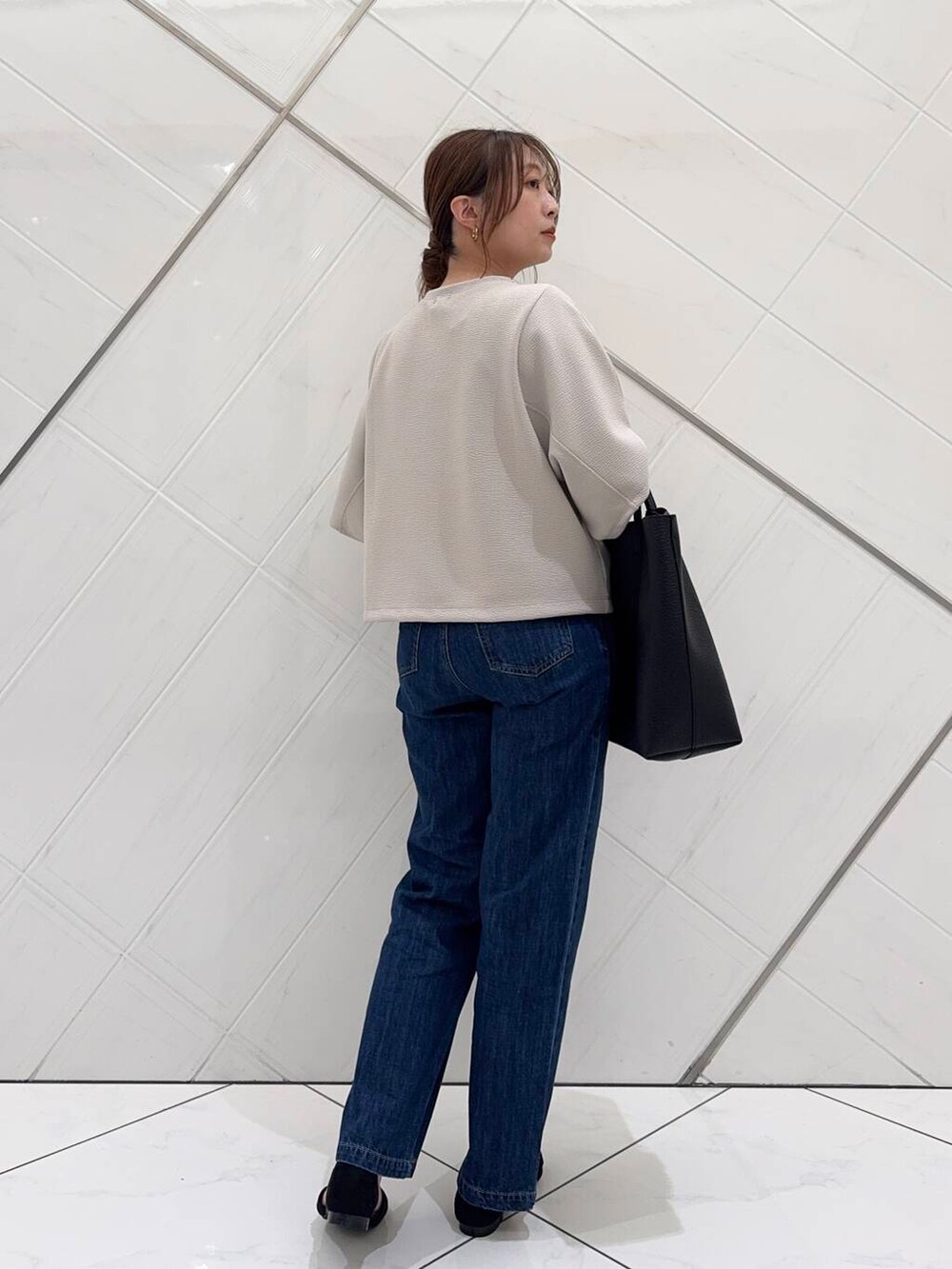 ブルー系のデニムパンツ、ブラック系のトートバッグ、ブラック系のサンダルを着用したレディースの春コーディネートの5枚目の写真