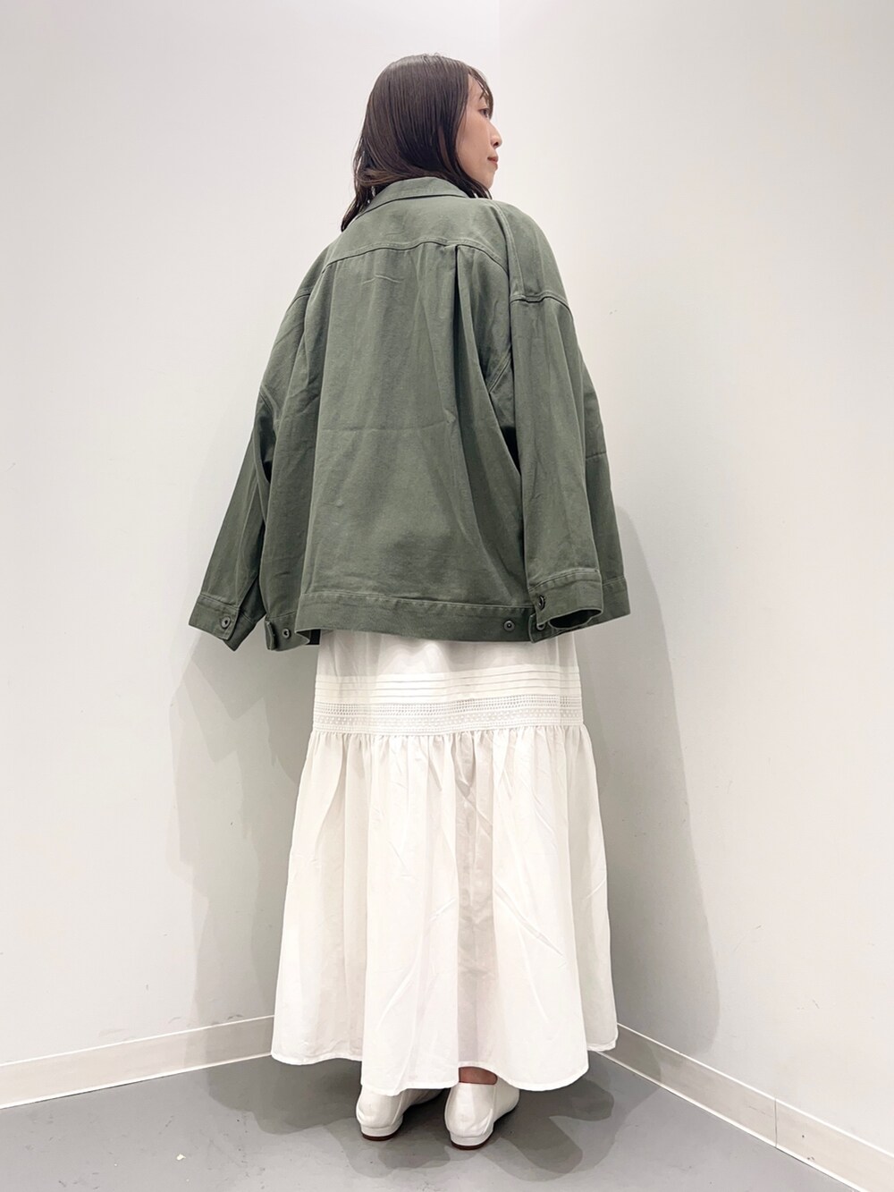 ベージュ系のスウェット、グリーン系のジャケット/アウター、ホワイト系のスカートを着用したレディースの夏コーディネートの4枚目の写真