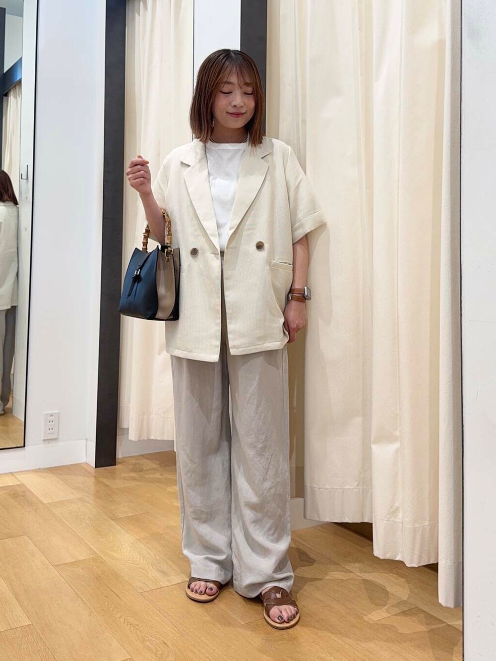 ブラウン系のサンダル、ベージュ系のその他パンツ、ブラック系のハンドバッグを着用したレディースの夏コーディネートの2枚目の写真