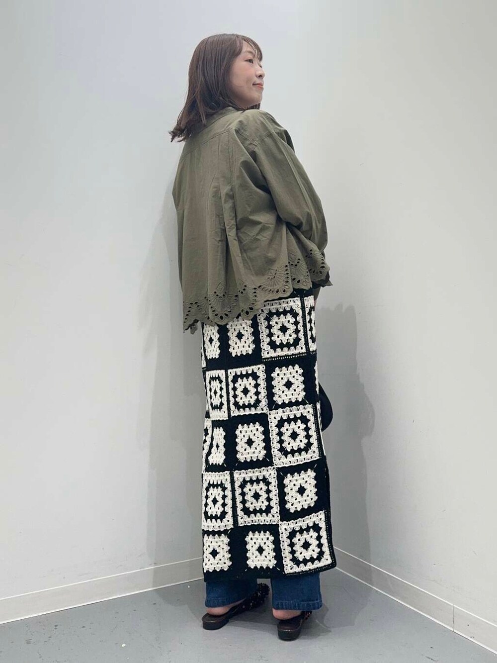 ブラック系のハンドバッグ、ブルー系のデニムパンツ、グリーン系のカーディガン/ボレロを着用したレディースの秋コーディネートの4枚目の写真