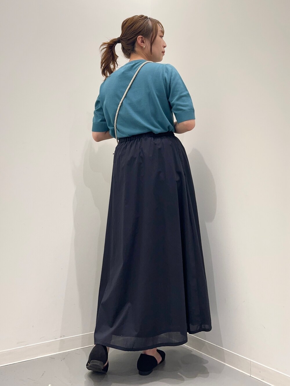 ブルー系のニット/セーター、ブルー系のスカート、ブラック系のサンダルを着用したレディースの春コーディネートの4枚目の写真