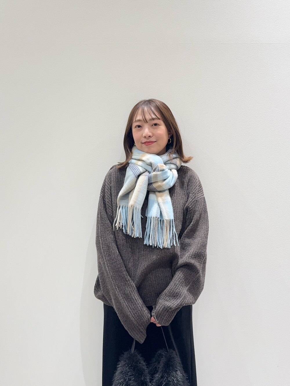 ブラウン系のニット/セーター、ブラック系のスカート、ブラック系のハンドバッグを着用したレディースの秋コーディネートの2枚目の写真