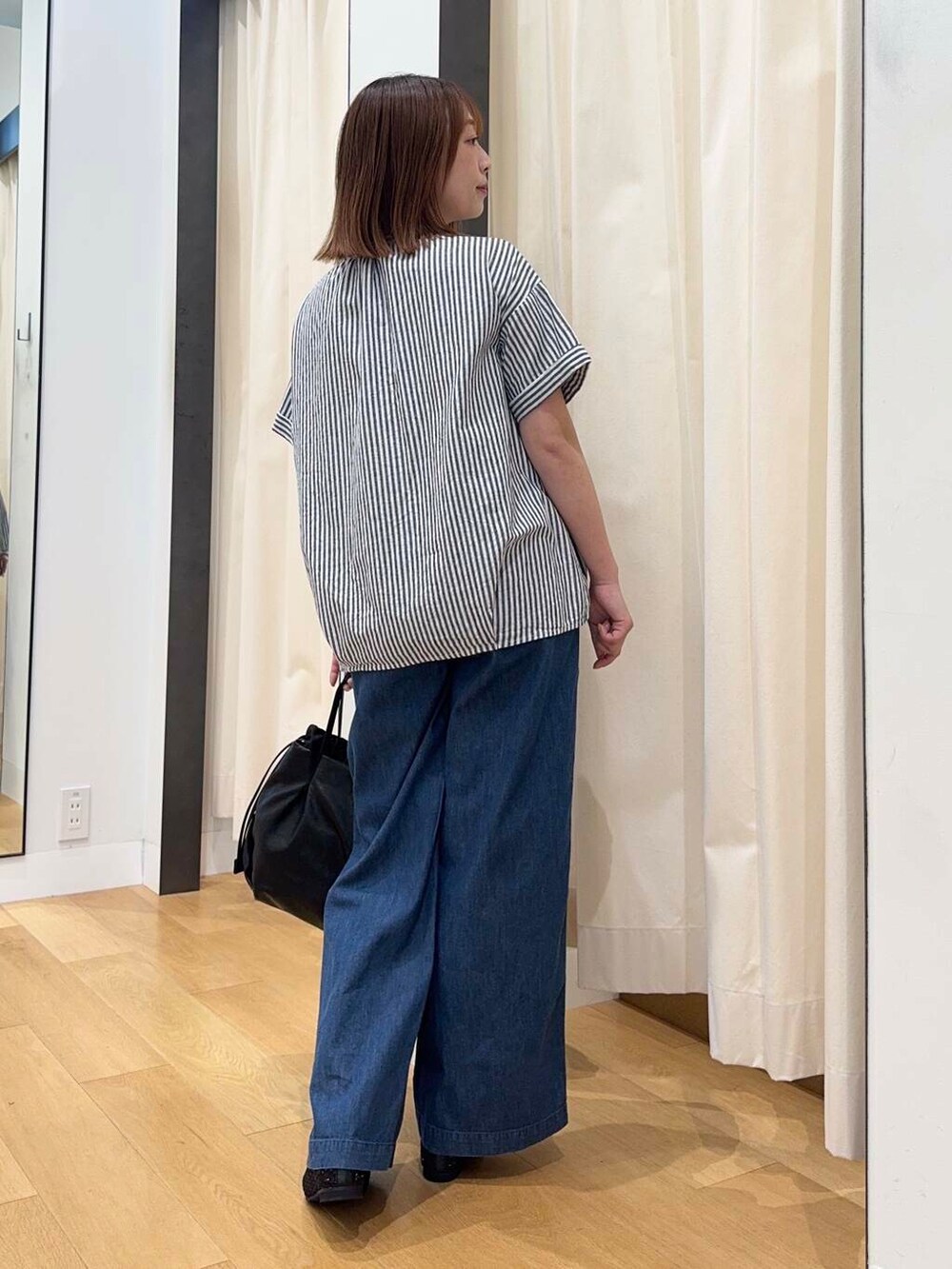 ブラック系のショルダーバッグ、ブルー系のデニムパンツ、ブラック系のバレエシューズを着用したレディースの夏コーディネートの4枚目の写真