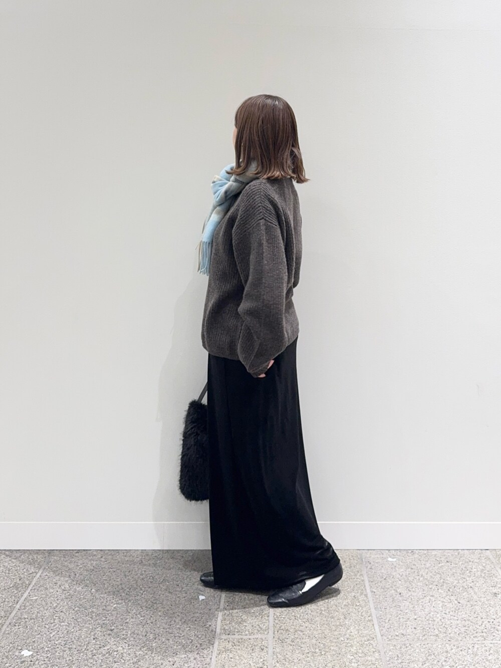 ブラウン系のニット/セーター、ブラック系のスカート、ブラック系のハンドバッグを着用したレディースの秋コーディネートの4枚目の写真