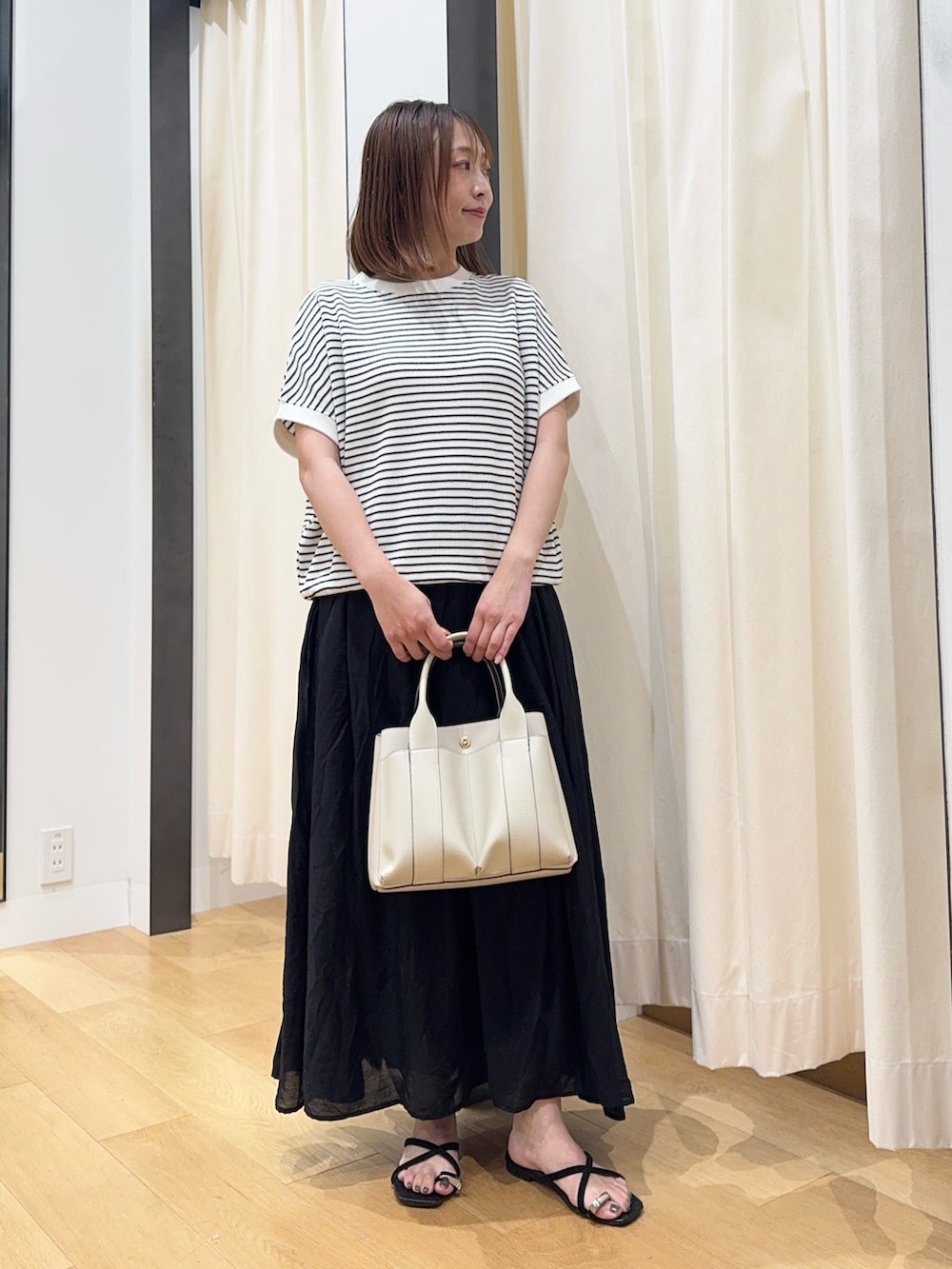 ホワイト系のTシャツ/カットソー、ブラック系のサンダル、ブラック系のスカートを着用したレディースの夏コーディネートの4枚目の写真