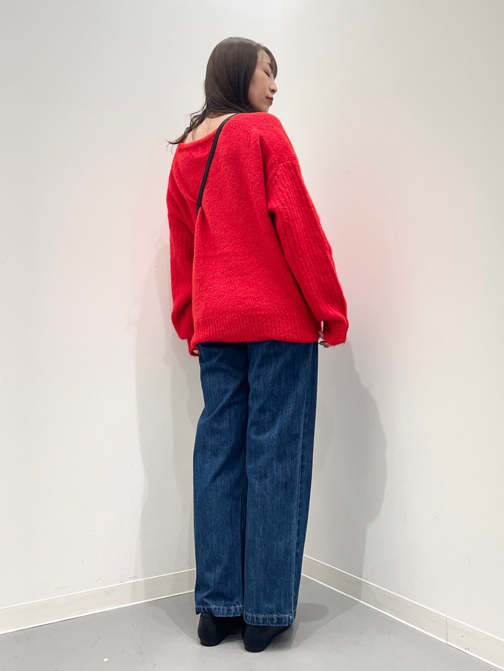 レッド系のニット/セーター、ブルー系のデニムパンツを着用したレディースの秋コーディネートの4枚目の写真