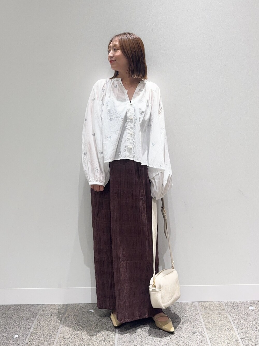 ホワイト系のシャツ/ブラウス、ブラウン系のスカート、ベージュ系のパンプスを着用したレディースの秋コーディネートの5枚目の写真