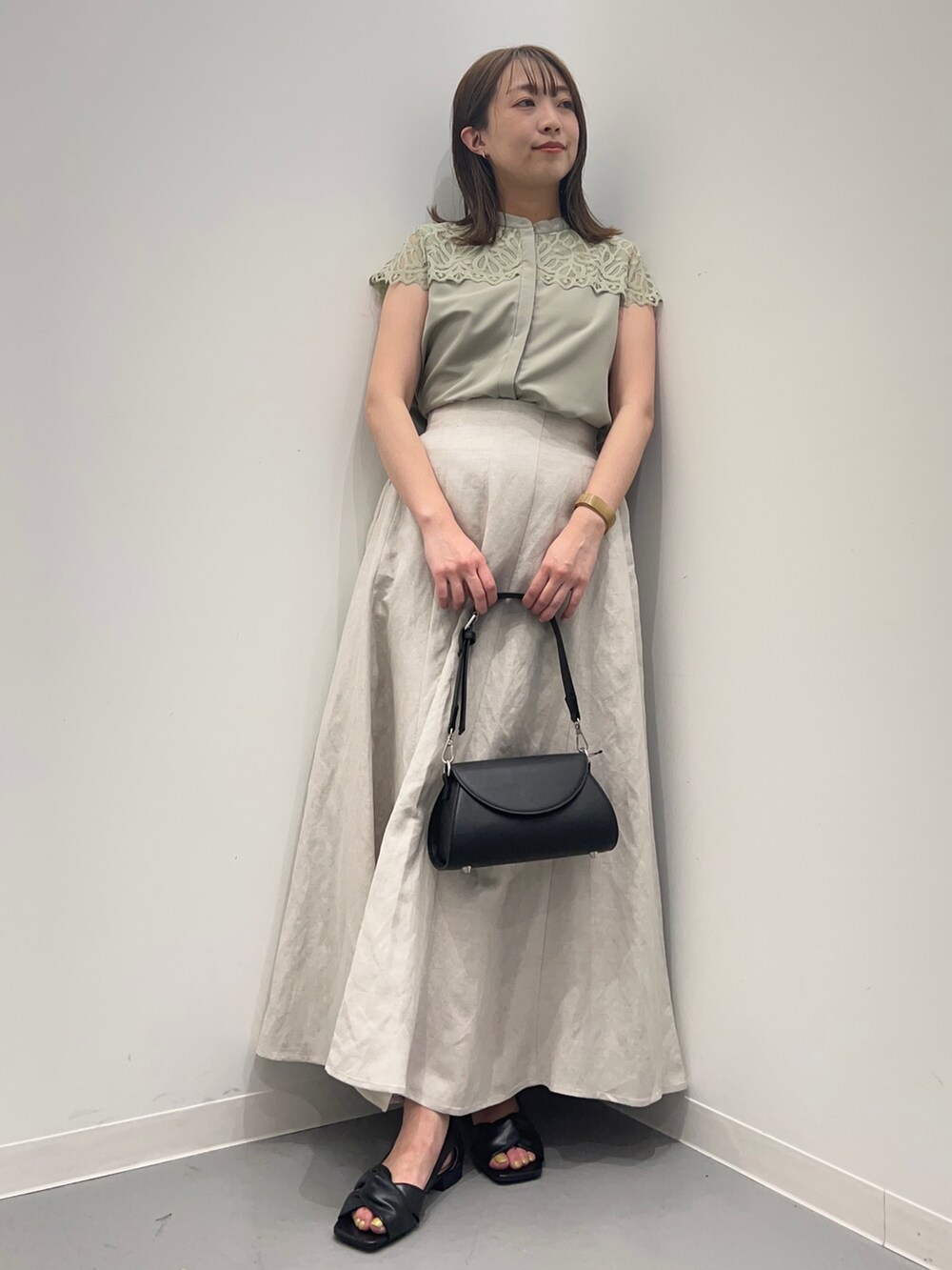 ホワイト系のスカート、グリーン系のシャツ/ブラウス、ブラック系のパンプスを着用したレディースの春コーディネートの3枚目の写真