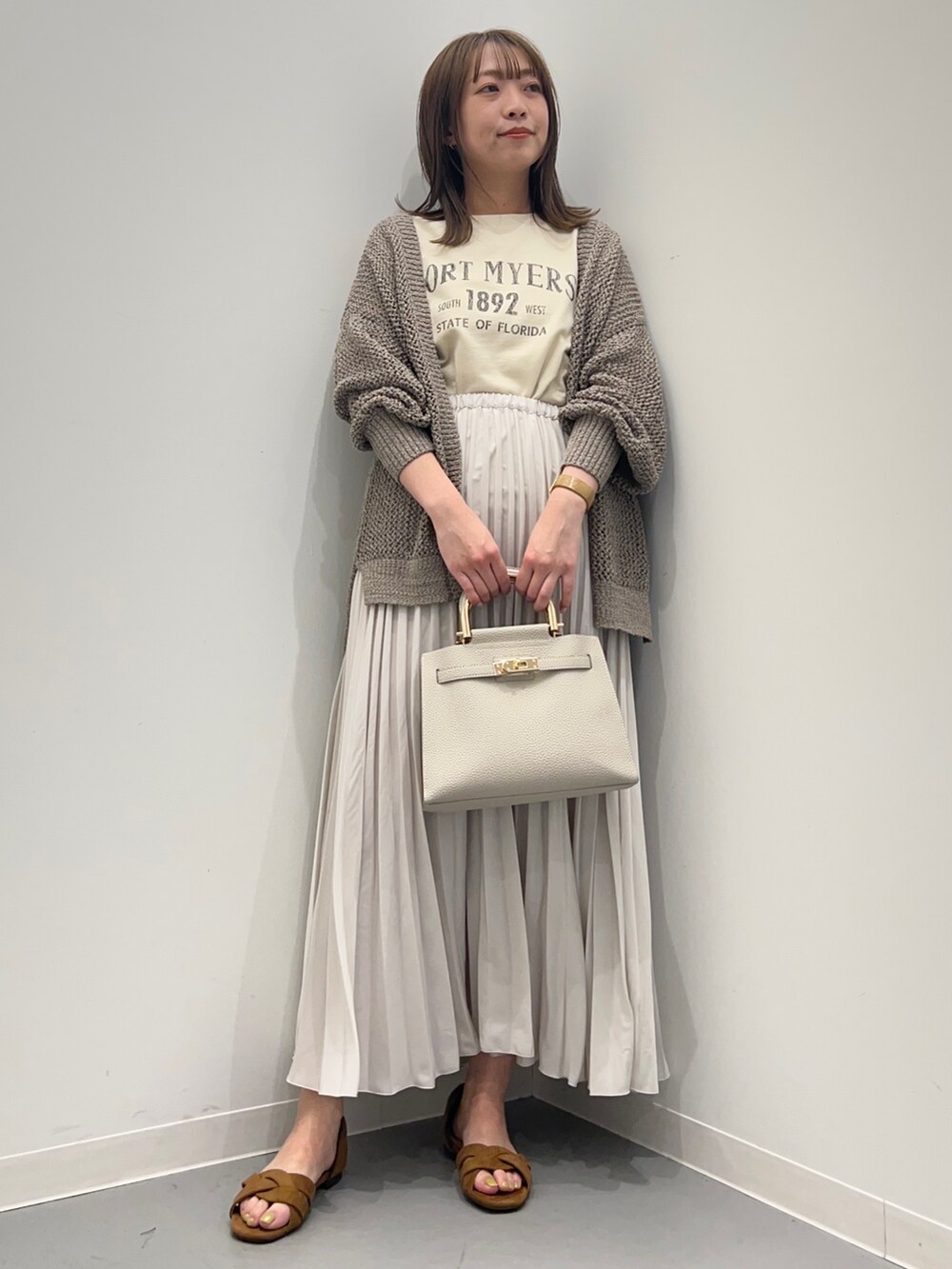 ベージュ系のTシャツ/カットソー、ホワイト系のスカート、グリーン系のカーディガン/ボレロを着用したレディースの春コーディネートの3枚目の写真