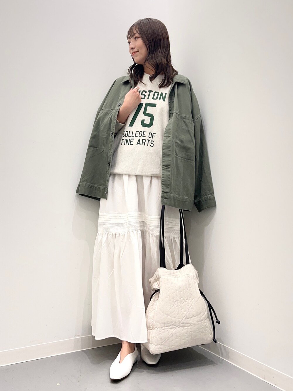 ベージュ系のスウェット、グリーン系のジャケット/アウター、ホワイト系のスカートを着用したレディースの夏コーディネートの2枚目の写真