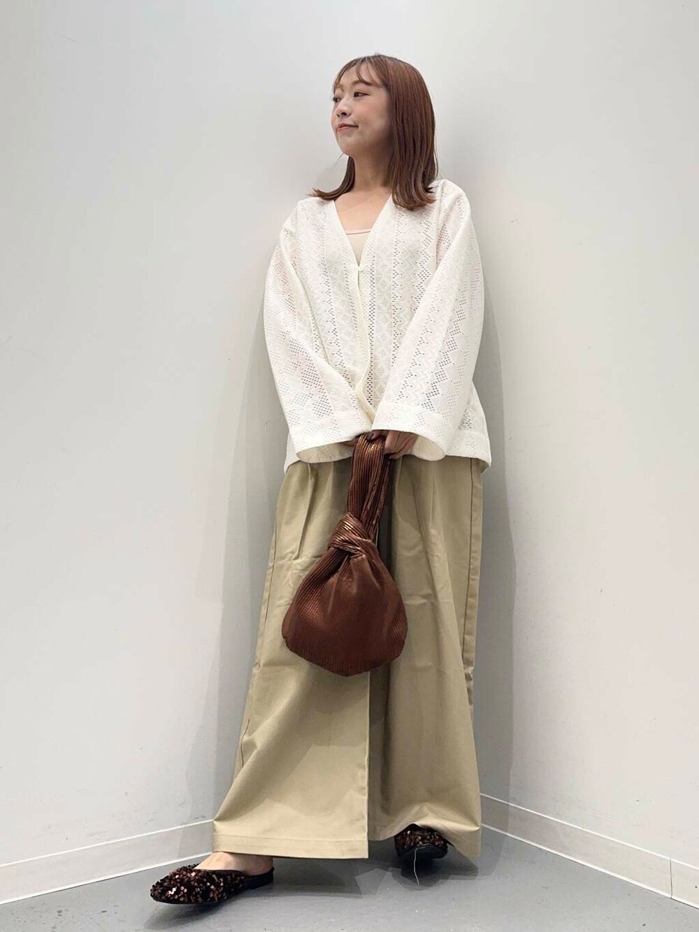 ブラウン系のハンドバッグ、ブラウン系のその他シューズ、ホワイト系のカーディガン/ボレロを着用したレディースの秋コーディネートの4枚目の写真