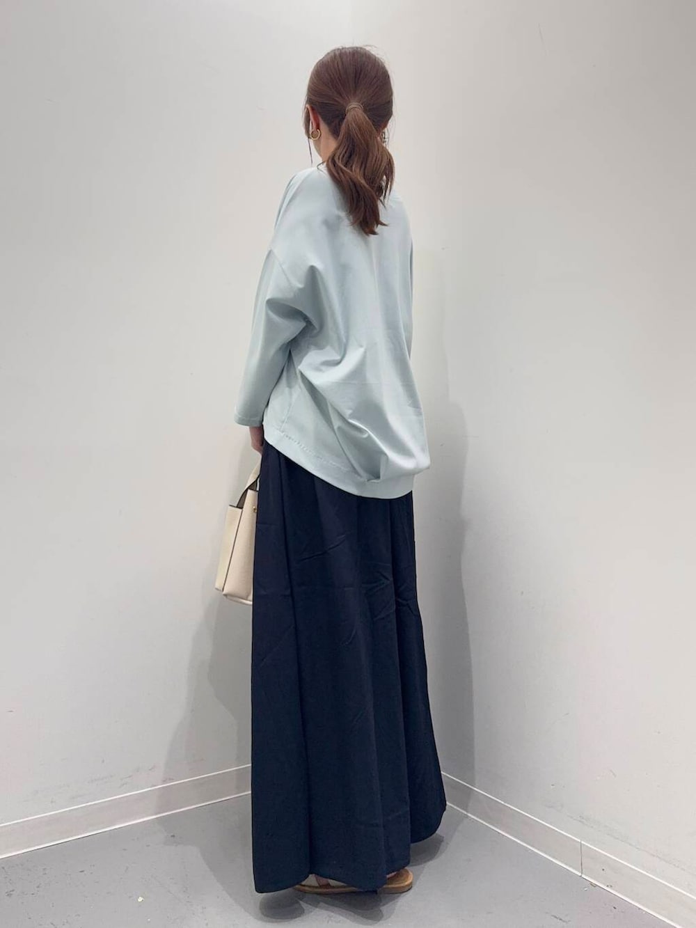 ホワイト系のトートバッグ、ブルー系のTシャツ/カットソー、ホワイト系のサンダルを着用したレディースの春コーディネートの3枚目の写真