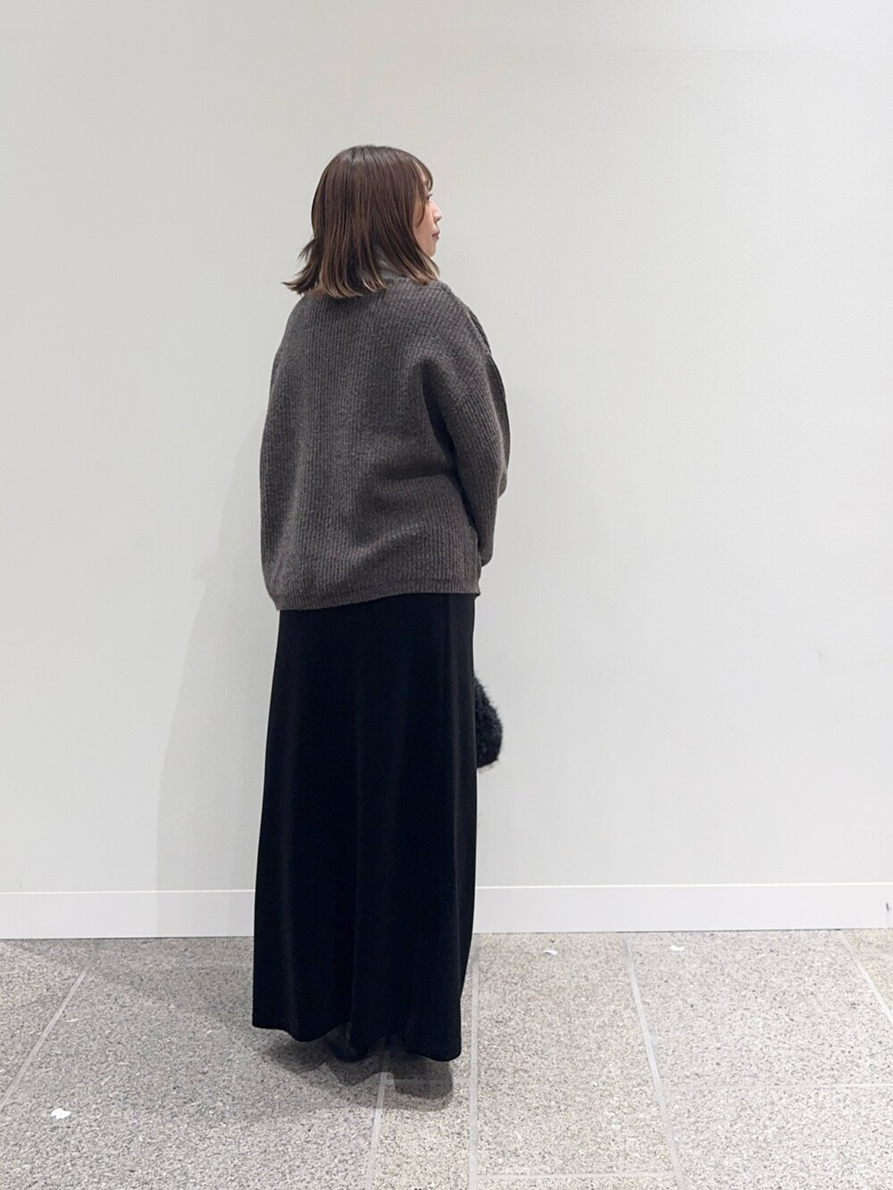 ブラウン系のニット/セーター、ブラック系のスカート、ブラック系のハンドバッグを着用したレディースの秋コーディネートの5枚目の写真