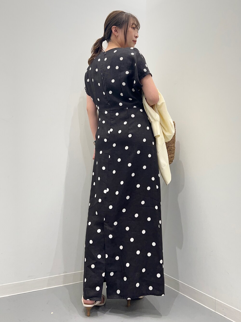 ブラック系のワンピース、ホワイト系のカーディガン/ボレロ、ベージュ系のかごバッグを着用したレディースの夏コーディネートの3枚目の写真