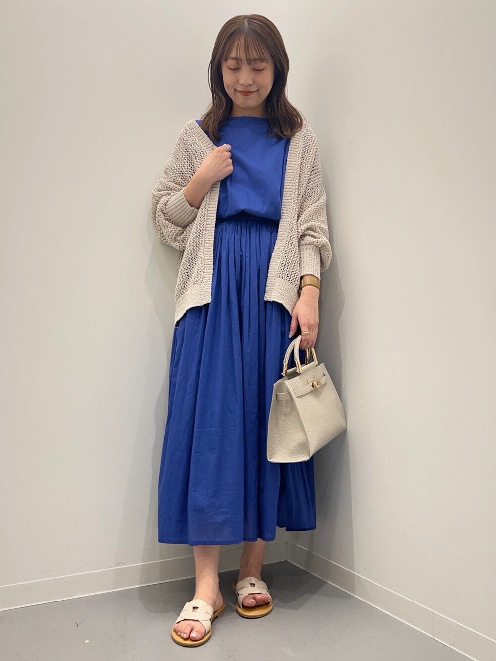 ブルー系のワンピース、ホワイト系のカーディガン/ボレロ、ホワイト系のハンドバッグを着用したレディースの夏コーディネートの2枚目の写真