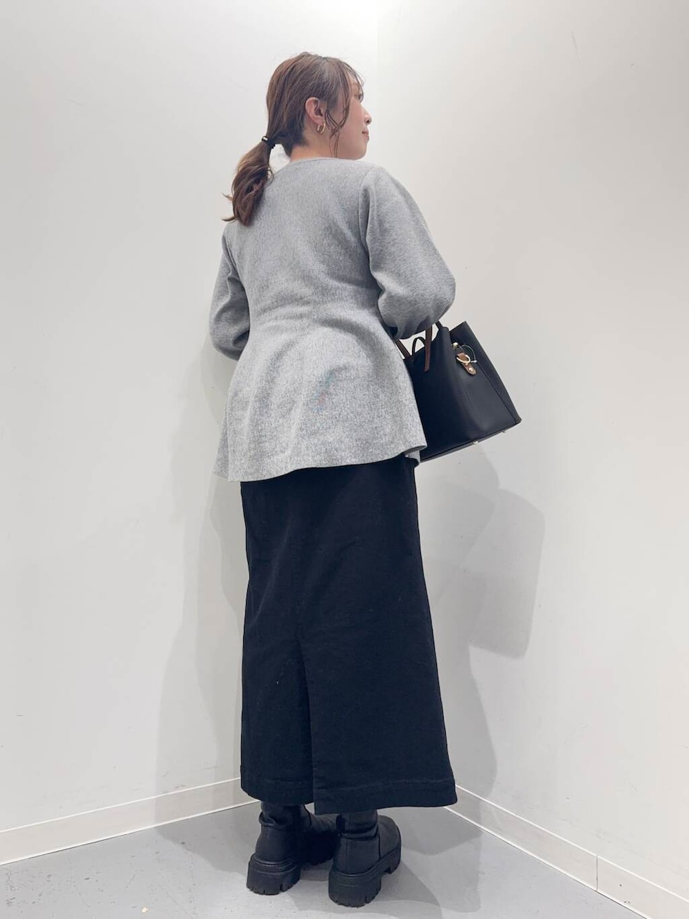 ブラック系のトートバッグ、ブラック系のブーツ、グレー系のニット/セーターを着用したレディースの冬コーディネートの3枚目の写真