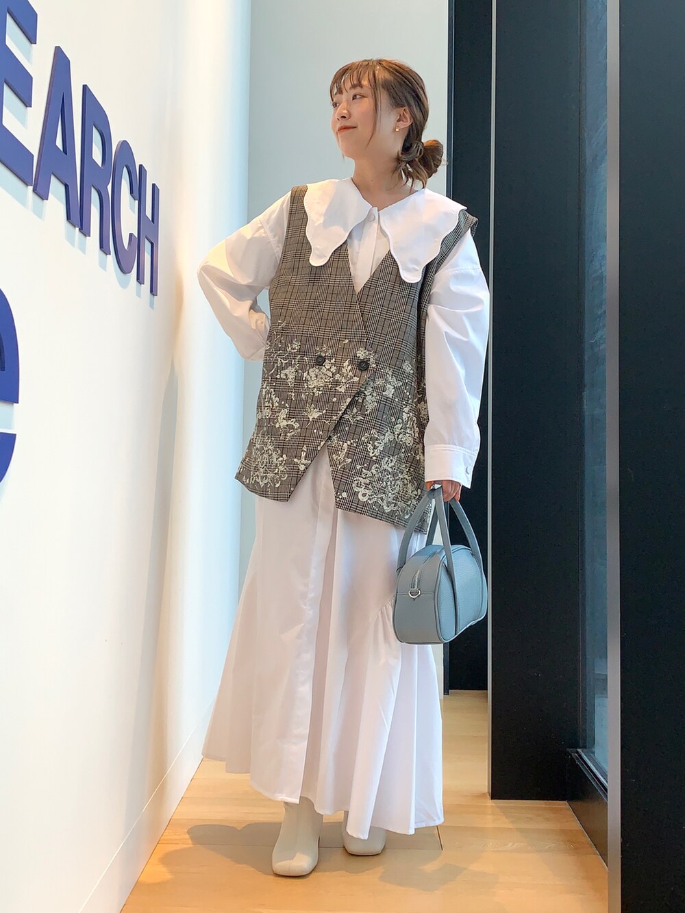 ブラウン系のベスト、ホワイト系のワンピースを着用したレディースの冬コーディネートの2枚目の写真